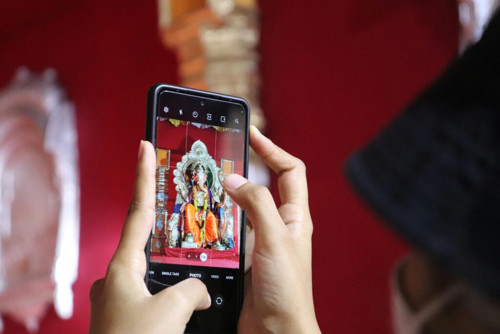 5 Emerging Cities for Art In 2025: Person Photographing Ganesha Statue in Mumbai with Smartphone